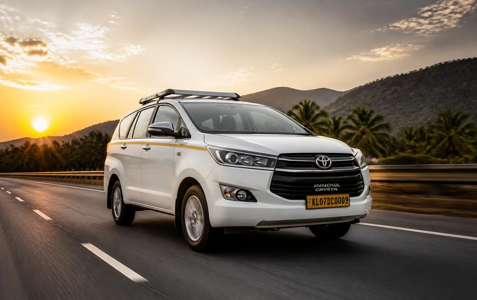 White Toyota Innova Crysta taxi on an Indian highway at sunrise